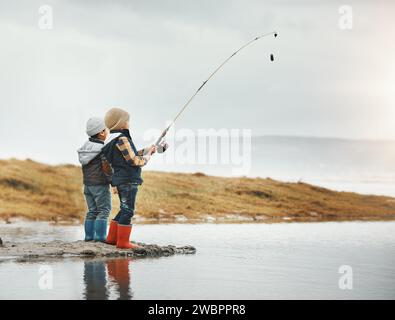 Lac, activité et pêche des enfants en vacances, aventure ou week-end pour un passe-temps. En plein air, nature et garçons frères ou enfants pêchant du poisson Banque D'Images