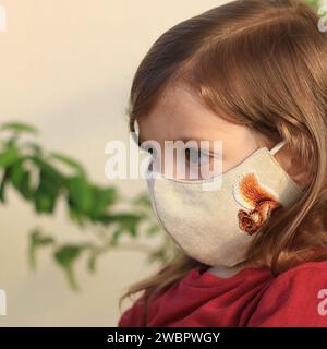 Un tout-petit aux poils longs portant un masque facial pendant la pandémie de Covid-19. Banque D'Images