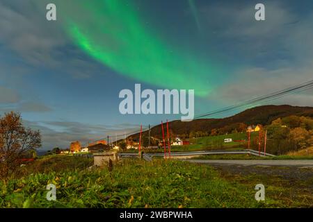Belles aurores boréales vertes sur un fjord et une maison sur l'île de Kvaloya près de Tromsø. danser des lumières polaires au-dessus d'une montagne, aurora borealis Banque D'Images