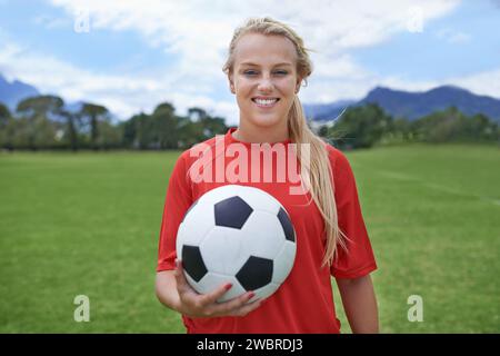 Femme, joueur de football et portrait avec ballon, confiance et terrain de football pour match, compétition ou jeu. Fitness, pratique et prêt pour l'entraînement Banque D'Images