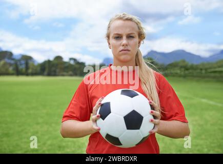 Femme, joueur de football et portrait avec ballon, confiance et terrain de football pour match, compétition ou jeu. Fitness, pratique et prêt pour l'entraînement Banque D'Images