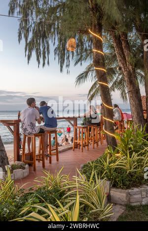 Personnes prenant un verre au bar de bord de mer Cassia Cottages, île de Phu Quoc, Vietnam. Banque D'Images