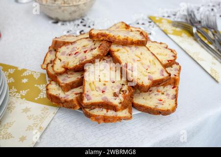 Gâteau fourré de bacon, jambon, olives et fromages jaunes tranché sur une nappe blanche, vue de côté Banque D'Images