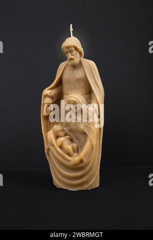 Bougie de cire naturelle en forme de mère Marie tenant le bébé Jésus, isolé sur fond noir, concept de décoration religieuse de noël Banque D'Images