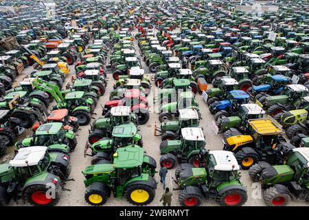 Nuremberg, Allemagne. 12 janvier 2024. De nombreux tracteurs sont garés lors d'un rassemblement d'associations d'agriculteurs contre les plans d'austérité du gouvernement fédéral à la Volksfestplatz (vue aérienne avec un drone). Le rassemblement fait partie d'actions de protestation nationales et est dirigé contre les coupes du gouvernement fédéral dans le diesel agricole et les véhicules agricoles. Crédit : Daniel Karmann/dpa/Alamy Live News Banque D'Images