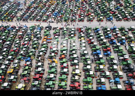 Nuremberg, Allemagne. 12 janvier 2024. De nombreux tracteurs sont garés lors d'un rassemblement d'associations d'agriculteurs contre les plans d'austérité du gouvernement fédéral à la Volksfestplatz (vue aérienne avec un drone). Le rassemblement fait partie d'actions de protestation nationales et est dirigé contre les coupes du gouvernement fédéral dans le diesel agricole et les véhicules agricoles. Crédit : Daniel Karmann/dpa/Alamy Live News Banque D'Images