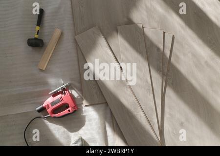 Marteau en caoutchouc, règle avec barre d'angle, mètre à ruban, scie sauteuse et autres outils pour l'installation du sol en vinyle stratifié. Amélioration de la maison, nouvelle installation de plancher Banque D'Images