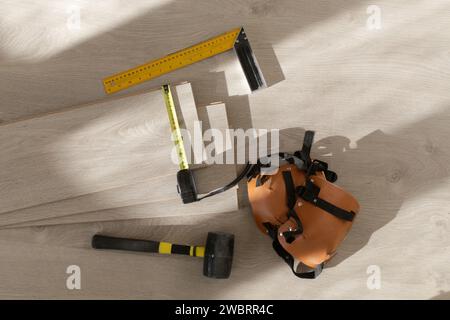 Marteau en caoutchouc, règle avec barre d'angle, mètre à ruban, scie sauteuse et autres outils pour l'installation du sol en vinyle stratifié. Amélioration de la maison, nouvelle installation de plancher Banque D'Images