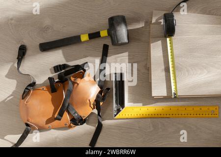 Marteau en caoutchouc, règle avec barre d'angle, mètre à ruban, scie sauteuse et autres outils pour l'installation du sol en vinyle stratifié. Amélioration de la maison, nouvelle installation de plancher Banque D'Images