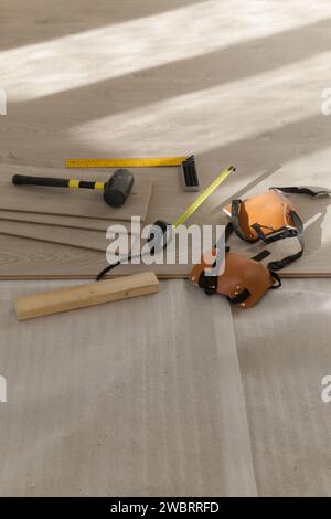 Marteau en caoutchouc, règle avec barre d'angle, mètre à ruban, scie sauteuse et autres outils pour l'installation du sol en vinyle stratifié. Amélioration de la maison, nouvelle installation de plancher Banque D'Images