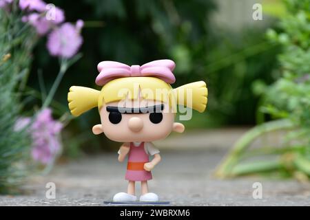 Funko Pop figurine d'action de Helga Pataki de la série télévisée d'animation Nickelodeon Hey Arnold. Jouet debout sur la route asphaltée dans le parc de printemps, fleurs roses. Banque D'Images