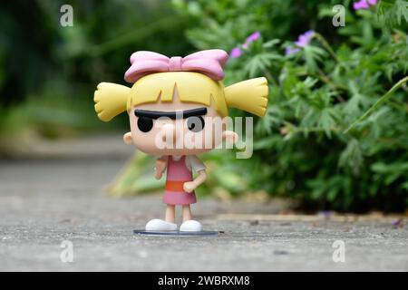 Funko Pop figurine d'action de Helga Pataki de la série télévisée d'animation Nickelodeon Hey Arnold. Jouet debout sur la route asphaltée dans le parc de printemps, fleurs roses. Banque D'Images