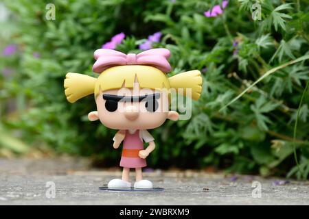 Funko Pop figurine d'action de Helga Pataki de la série télévisée d'animation Nickelodeon Hey Arnold. Jouet debout sur la route asphaltée dans le parc de printemps, fleurs roses. Banque D'Images