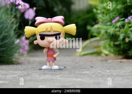 Funko Pop figurine d'action de Helga Pataki de la série télévisée d'animation Nickelodeon Hey Arnold. Jouet debout sur la route asphaltée dans le parc de printemps, fleurs roses. Banque D'Images