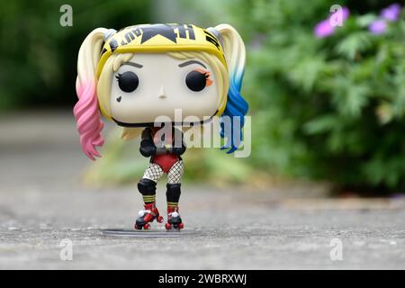 Figurine Funko Pop de Harley Quinn du film DC Birds of Prey. Jouet en vinyle avec casque et patins à roulettes debout sur la route asphaltée dans le parc vert. Banque D'Images