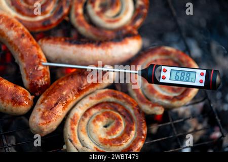 Gros plan d'un thermomètre à viande numérique affichant une température de cuisson sûre pour les saucisses grillées Banque D'Images