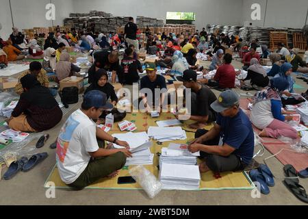 Magelang, Java central, Indonésie. 11 janvier 2024. Un travailleur plie des bulletins de vote et montre des photos de candidats à la présidence sur des bulletins de vote pour l'élection présidentielle du 14 février montrant les candidats, de gauche à droite, Anies Baswedan et son coéquipier Muhaimin Iskandar, Prabowo Subianto et son coéquipier Gibran Rakabuming Raka, et Ganjar Pranowo et son coéquipier Mahfud MD, lors des préparatifs pour la distribution de la logistique électorale à Magelang, Java central, le 11 janvier 2024. La troisième plus grande démocratie du monde a établi la liste électorale permanente (DPT) pour l'élection générale de 2024 à 20 Banque D'Images