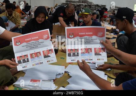 Magelang, Java central, Indonésie. 11 janvier 2024. Un travailleur plie des bulletins de vote et montre des photos de candidats à la présidence sur des bulletins de vote pour l'élection présidentielle du 14 février montrant les candidats, de gauche à droite, Anies Baswedan et son coéquipier Muhaimin Iskandar, Prabowo Subianto et son coéquipier Gibran Rakabuming Raka, et Ganjar Pranowo et son coéquipier Mahfud MD, lors des préparatifs pour la distribution de la logistique électorale à Magelang, Java central, le 11 janvier 2024. La troisième plus grande démocratie du monde a établi la liste électorale permanente (DPT) pour l'élection générale de 2024 à 20 Banque D'Images
