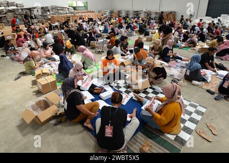Magelang, Java central, Indonésie. 11 janvier 2024. Un travailleur plie des bulletins de vote et montre des photos de candidats à la présidence sur des bulletins de vote pour l'élection présidentielle du 14 février montrant les candidats, de gauche à droite, Anies Baswedan et son coéquipier Muhaimin Iskandar, Prabowo Subianto et son coéquipier Gibran Rakabuming Raka, et Ganjar Pranowo et son coéquipier Mahfud MD, lors des préparatifs pour la distribution de la logistique électorale à Magelang, Java central, le 11 janvier 2024. La troisième plus grande démocratie du monde a établi la liste électorale permanente (DPT) pour l'élection générale de 2024 à 20 Banque D'Images