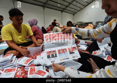 Magelang, Java central, Indonésie. 11 janvier 2024. Un travailleur plie des bulletins de vote et montre des photos de candidats à la présidence sur des bulletins de vote pour l'élection présidentielle du 14 février montrant les candidats, de gauche à droite, Anies Baswedan et son coéquipier Muhaimin Iskandar, Prabowo Subianto et son coéquipier Gibran Rakabuming Raka, et Ganjar Pranowo et son coéquipier Mahfud MD, lors des préparatifs pour la distribution de la logistique électorale à Magelang, Java central, le 11 janvier 2024. La troisième plus grande démocratie du monde a établi la liste électorale permanente (DPT) pour l'élection générale de 2024 à 20 Banque D'Images