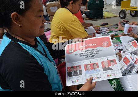 Magelang, Java central, Indonésie. 11 janvier 2024. Un travailleur plie des bulletins de vote et montre des photos de candidats à la présidence sur des bulletins de vote pour l'élection présidentielle du 14 février montrant les candidats, de gauche à droite, Anies Baswedan et son coéquipier Muhaimin Iskandar, Prabowo Subianto et son coéquipier Gibran Rakabuming Raka, et Ganjar Pranowo et son coéquipier Mahfud MD, lors des préparatifs pour la distribution de la logistique électorale à Magelang, Java central, le 11 janvier 2024. La troisième plus grande démocratie du monde a établi la liste électorale permanente (DPT) pour l'élection générale de 2024 à 20 Banque D'Images