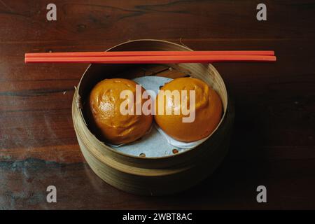 Petit pain cuit à la vapeur avec limage au jaune d'œuf également connu sous le nom de Bakpao Telur ASIN sur une table en bois Banque D'Images