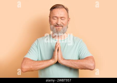 Photo d'un homme concentré concentré montrant deux mains ensemble rêvant de demander de l'aide isolé sur fond beige Banque D'Images
