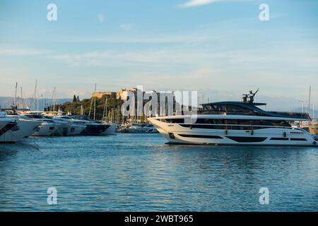 Super yachts de luxe amarrés au port de plaisance de Port Vauban, Antibes. Un bateau manœuvre dans le port, surplombé par le fort carré en forme d'étoile. France. (135) Banque D'Images