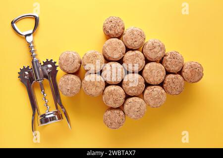 Bouchons de vin en forme de chevrons et tire-bouchon en métal sur fond jaune. Une flèche faite de bouchons de vin indique la direction Banque D'Images