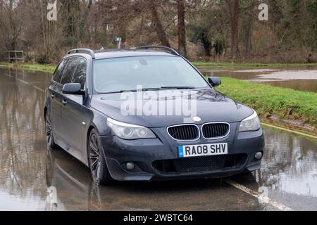 Cookham, Royaume-Uni. 6 janvier 2024. Une BMW noire abandonnée reste dans les eaux de crue sur la route principale B4447 à travers Cookham Moor dans le village de Cookham, Berkshire après de vastes inondations cette semaine. Une page GoFundMe a été créée pour le propriétaire de la voiture par les résidents locaux. Crédit : Maureen McLean/Alamy Live News Banque D'Images