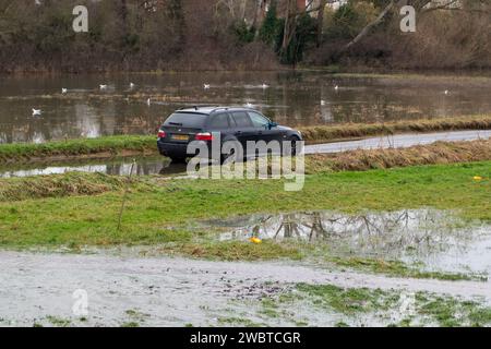 Cookham, Royaume-Uni. 6 janvier 2024. Une BMW noire abandonnée reste dans les eaux de crue sur la route principale B4447 à travers Cookham Moor dans le village de Cookham, Berkshire après de vastes inondations cette semaine. Une page GoFundMe a été créée pour le propriétaire de la voiture par les résidents locaux. Crédit : Maureen McLean/Alamy Live News Banque D'Images