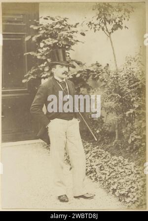Portrait d'un Français avec un chapeau haut de gamme, un bâton de marche et un cigare, debout, c. 1900 - c. 1910 photographie partie de l'album photo d'un photographe amateur français avec des enregistrements d'une famille, distillerie Delizy & Doistau fils, l'armée et les sites en France. Papier France. support photographique de l'albumine homme adulte. casque : chapeau haut de gamme. cigare. bâton de marche, personnel. Main dans la poche - AA - les deux bras ou mains France Banque D'Images