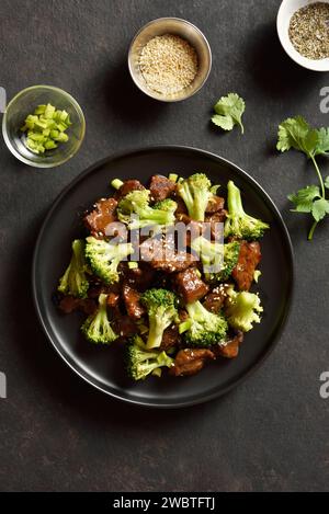 Bœuf de style asiatique avec brocoli sur plaque noire sur fond de pierre sombre. Viande de bœuf finement tranchée avec brocoli rôti. Plat de bœuf sauté. Top vie Banque D'Images