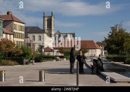 Les filles se détendent près des fontaines ornementales sur la place de la libération à Troyes, en France avec la cathédrale Saint-Pierre et Saint-Paul en arrière-plan. Banque D'Images