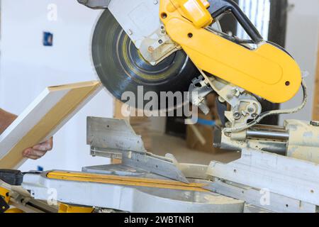 Découpe de moulures en bois de base du projet d'amélioration de la maison à l'aide d'une scie à découper Banque D'Images