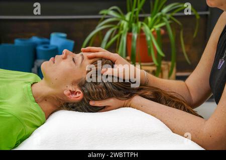 Au milieu du traitement Reiki thérapeute donnant à la femme sur le visage au spa Banque D'Images