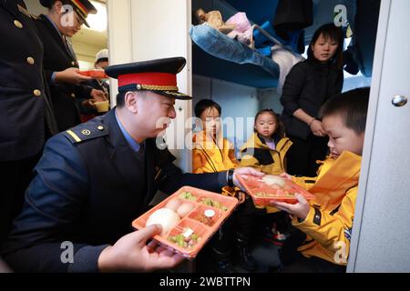 (240112) -- HARBIN, 12 janv. 2024 (Xinhua) -- le chef d'orchestre Zhang Yong offre un petit déjeuner aux enfants de la région autonome de Guangxi Zhuang, dans le sud de la Chine, à bord du train K7042, un train qui part de Mohe et se dirige vers Harbin, dans la province de Heilongjiang, dans le nord-est de la Chine, le 6 janvier 2024. Ces enfants mignons sont surnommés « petites mandarines à sucre » (une spécialité du Guangxi) par les internautes chinois. Onze enfants d'âge préscolaire de Nanning, la capitale de la région autonome de Guangxi Zhuang, dans le sud de la Chine, ont capturé le cœur des internautes chinois alors qu'ils embarquent dans un camp « courageux » dans le nord-est de Chin Banque D'Images