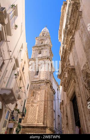 Vue sur la rue du centre historique de Monopoli dans les Pouilles, Italie : aperçu du clocher de la cathédrale Maria Santissima della Madia. Banque D'Images