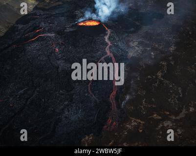 Vue unique sur le volcan en éruption et ses environs, lave rouge bouillante coulant, tir de drone. Catastrophe naturelle, environnement et climat ch Banque D'Images