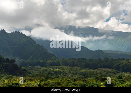 Des nuages énigmatiques ornent les sommets de Maui, mettant en valeur le paysage dynamique de l'île et la riche forêt tropicale humide. Banque D'Images