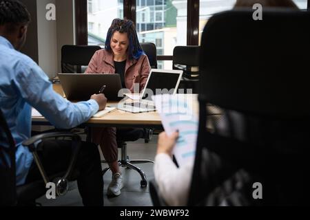 Femme souriante IT Sphere travailleur avec les cheveux tressés travaillant avec des collègues Banque D'Images