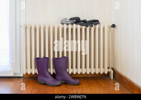 Bottes et accessoires d'hiver séchant sur un radiateur en fonte Banque D'Images