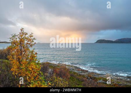 Un front de pluie s’approche de l’île de Sommarøy de l’autre côté de l’Atlantique. nuages colorés au coucher du soleil avec des nuages pluvieux roses et oranges, bleus et noirs Banque D'Images