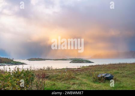 Un front de pluie s’approche de l’île de Sommarøy de l’autre côté de l’Atlantique. nuages colorés au coucher du soleil avec des nuages pluvieux roses et oranges, bleus et noirs Banque D'Images