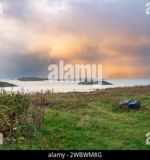 Un front de pluie s’approche de l’île de Sommarøy de l’autre côté de l’Atlantique. nuages colorés au coucher du soleil avec des nuages pluvieux roses et oranges, bleus et noirs Banque D'Images