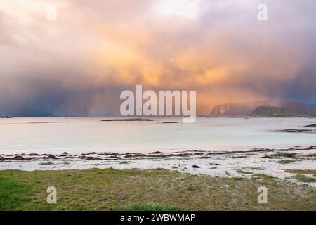 Un front de pluie s’approche de l’île de Sommarøy de l’autre côté de l’Atlantique. nuages colorés au coucher du soleil avec des nuages pluvieux roses et oranges, bleus et noirs Banque D'Images