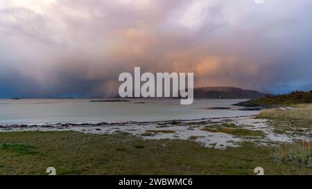 Un front de pluie s’approche de l’île de Sommarøy de l’autre côté de l’Atlantique. nuages colorés au coucher du soleil avec des nuages pluvieux roses et oranges, bleus et noirs Banque D'Images