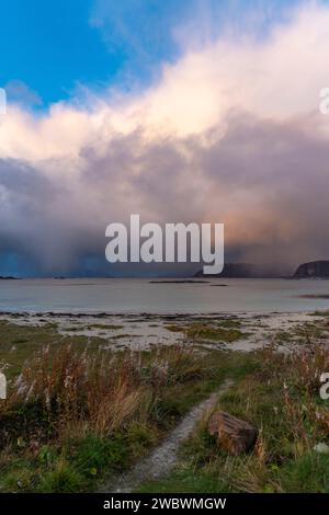 Un front de pluie s’approche de l’île de Sommarøy de l’autre côté de l’Atlantique. nuages colorés au coucher du soleil avec des nuages pluvieux roses et oranges, bleus et noirs Banque D'Images