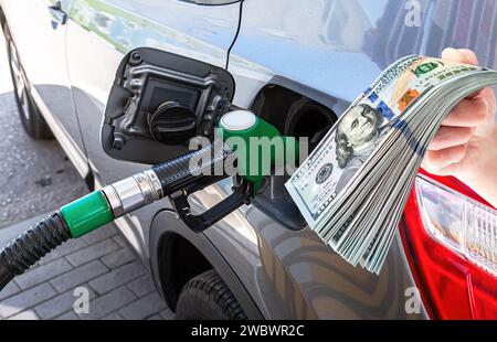 Buse de carburant pour libérer le carburant dans la voiture de tourisme à la station-service et dollars Banque D'Images