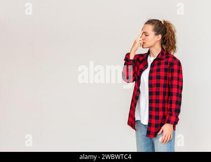 Femme en chemise rouge se tient devant le fond simple et faire de l'exercice de respiration. Toucher l'arête du nez avec le doigt. Faire face au stress. Str Banque D'Images